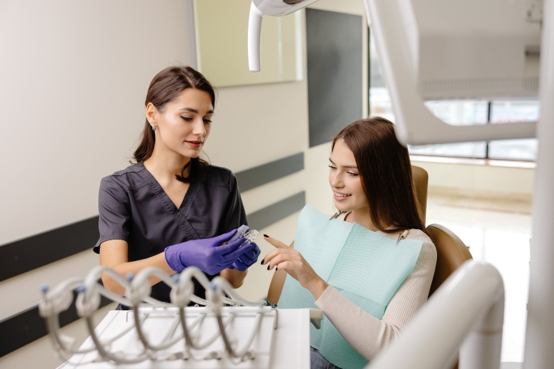 A woman seated in a dental chair discusses Invisalign treatment with a dentist in San Jose, CA